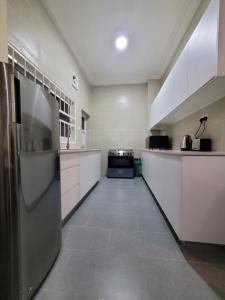 a large kitchen with white cabinets and a stainless steel refrigerator at Chez Chic Apartments in Sere Kunda