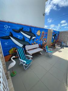 un mural en el lateral de un edificio con sillas y una pared en Casa De Praia em Itamaracá, en Itamaracá