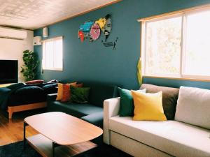 ein Wohnzimmer mit Sofa und Tisch in der Unterkunft 恩納村名嘉真フォレストヴィラ12時チェックアウト可ダブルベッド2台と2段ベッドとユニットバス2室 in Onna