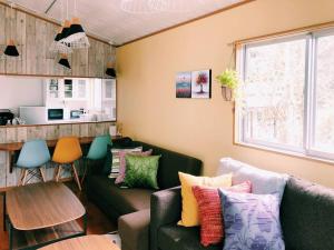 ein Wohnzimmer mit zwei Sofas und einem Tisch in der Unterkunft 恩納村名嘉真フォレストヴィラ12時チェックアウト可ダブルベッド2台と2段ベッドとユニットバス2室 in Onna