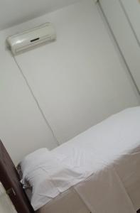 a bed in a room with a white bedsheet at Apto Olinda Casa Caiada ao lado do Shopping in Olinda