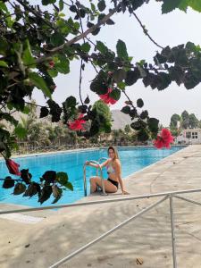 a woman in a bikini sitting next to a swimming pool at Mi Pequeño Club (Country Club) in Lima