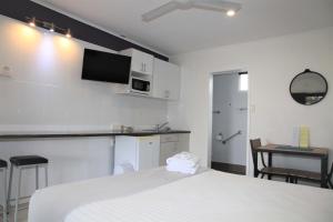a white kitchen with a white refrigerator and a white tv at Charm City Motel in Bundaberg