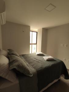 a bedroom with a bed with two pillows and a window at Apto climatizado à beira-mar c/ piscina-Intermares in Cabedelo