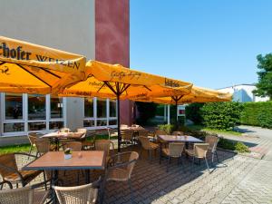 eine Außenterrasse mit Tischen, Stühlen und Sonnenschirmen in der Unterkunft ACHAT Hotel Schwarzheide Lausitz in Schwarzheide