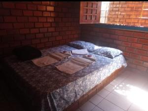 een bed in een kamer met een bakstenen muur bij Prive das Acacias in Porto De Galinhas