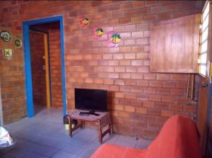 Camera con parete in mattoni, tavolo e TV. di Prive das Acacias a Porto De Galinhas