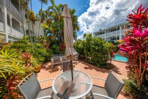 een tafel met een parasol en stoelen en een zwembad bij City Terraces Cairns in Cairns