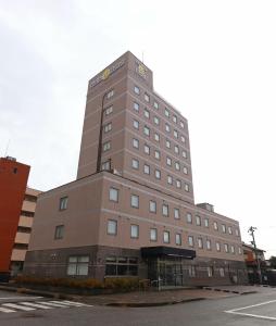 a tall brown building sitting on the side of a street at Smile Hotel Takaoka Ekimae in Takaoka