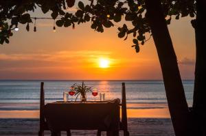 - une table sur la plage avec un coucher de soleil en arrière-plan dans l'établissement Klongdao Sunset Villa, à Ko Lanta