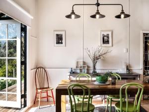 a dining room with a wooden table and green chairs at Table Hill Cottage - dog friendly retreat in Daylesford