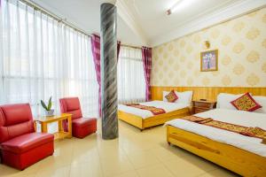 una camera d'albergo con due letti e una sedia di Khanh Hong Da Lat a Da Lat