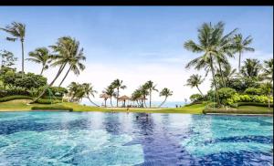 a pool with palm trees and the ocean in the background at 16 Forest City homestay-free WIFI-森林城市民宿 in Johor Bahru