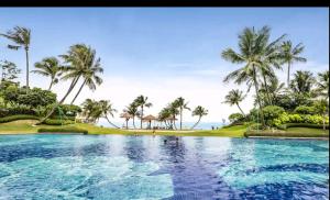 uma piscina com palmeiras e o oceano ao fundo em 16 Forest City homestay-free WIFI-森林城市民宿 em Johor Bahru