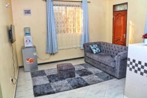 een woonkamer met een bank en een televisie bij Nice Spacious 1bedroom hideout in bamburi in Mombasa