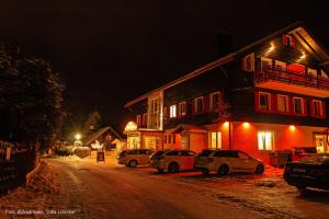 uma rua à noite com carros estacionados em frente a um edifício em Harmonie Hotel Rust em Hohegeiß
