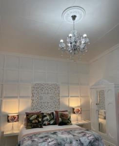 1 dormitorio con cama y lámpara de araña en Jelani Guest House en White River