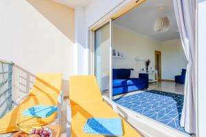 Zimmer mit einem Balkon mit gelben Stühlen und einem Wohnzimmer. in der Unterkunft Ocean view Apartment with 3 spacious Terraces, 2 Swimming pools & Tennis court in Albufeira