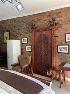 a room with a brick wall with a refrigerator and a door at Jelani Guest House in White River