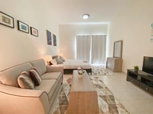 a living room with a couch and a tv at Stylish Studio Vacation Home near Metro - JHN in Dubai