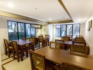 un restaurante con mesas y sillas de madera y ventanas en Treebo Trend Time Square Marine Drive, en Kochi
