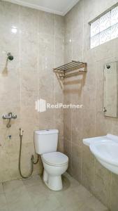 a bathroom with a toilet and a sink at Palu City Guest House Mitra RedDoorz in Palu