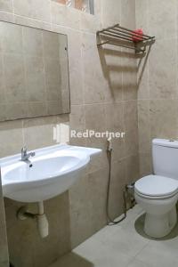 bagno con lavandino, servizi igienici e specchio di Palu City Guest House Mitra RedDoorz a Palu