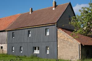 Une grande grange noire avec un toit brun dans l'établissement Ferienhaus Brockenblick, à Hüttenrode