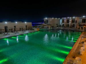 a swimming pool at night with green lights in it at Mirage Bab Al Bahr Beach Resort in Dibba