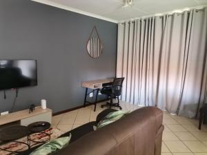 Una sala de estar con un sofá y un escritorio. en Centurion Cosy Apartment, en Centurion