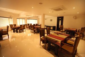 un comedor con mesas, sillas y mesa de comedor en Loveland Residency en Ernakulam