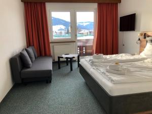a hotel room with a bed and a chair and a window at Sportpension Therese in Westendorf