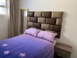a bedroom with a purple bed with a large mirror at Tenbury Beach Apartment in Durban +17 photos