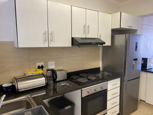 a kitchen with white cabinets and a stainless steel refrigerator at Tenbury Beach Apartment in Durban