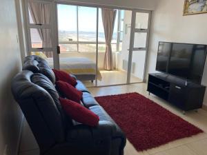 a living room with a couch and a flat screen tv at Tenbury Beach Apartment in Durban