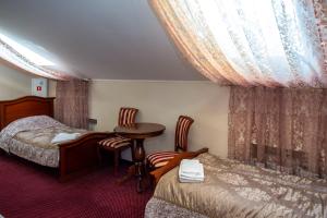 een hotelkamer met 2 bedden en een tafel en stoelen bij Старый Симбирск in Ulyanovsk