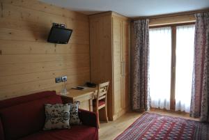 un salon avec un canapé rouge et une télévision dans l'établissement Hotel de Gletscher, à Gressoney-La-Trinité