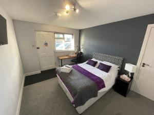 a bedroom with a bed with purple sheets and a window at Arlan House, Central Basingstoke Hotel in Basingstoke