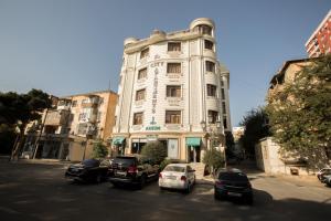 un grand bâtiment blanc avec des voitures garées devant lui dans l'établissement City Apartments, à Baku
