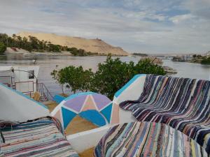 dos sillas y sombrillas sentadas junto a un río en Baba Dool en Asuán