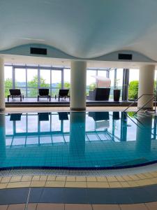 a swimming pool with tables and benches in a building at Phönix Hotel in Bergneustadt