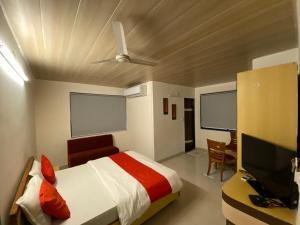 a bedroom with a bed and a desk and a television at Hotel Riverfront in Ahmedabad