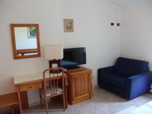 a room with a blue chair a desk and a tv at Il Gabbiano in Chia