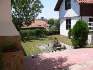 a yard with a stone fountain in front of a house at Madara Club and Spa in Kosharitsa