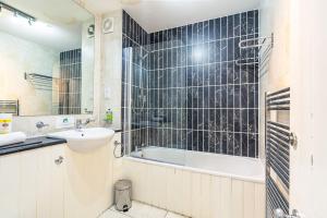a bathroom with a bath tub and a sink and a mirror at Tron Kirk Residence in Edinburgh +69 photos