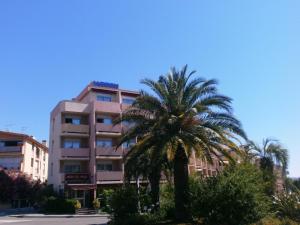 un edificio alto con palmeras delante en Hôtel Maya en Cavalaire-sur-Mer