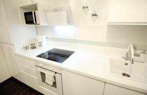 a white kitchen with a sink and a microwave at SECRET HIDEAWAYS Space Loft Wohndesign auf 2 Etagen l 450m bis Uni in Duisburg