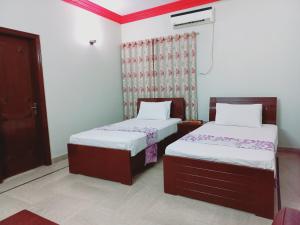 um quarto com 2 camas e uma janela em Rose Palace Millennium em Karachi