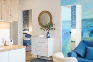 ein Wohnzimmer mit einem blauen Sofa und einem Spiegel in der Unterkunft Sunset Resort II, Nadmorska 104 in Grzybowo