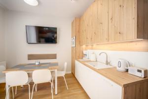 a kitchen with a sink and a table with chairs at Sunset Resort II, Nadmorska 104 in Grzybowo